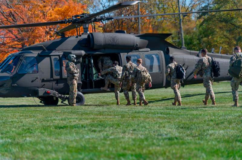 a group of people in military uniforms walking out of a helicopter