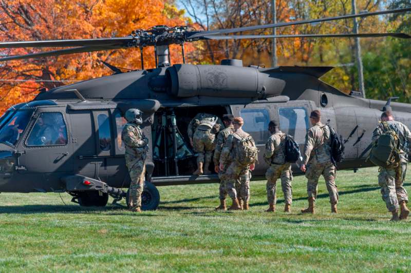 a group of people in military uniforms getting off a helicopter