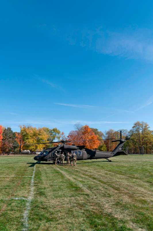 a group of people standing next to a helicopter