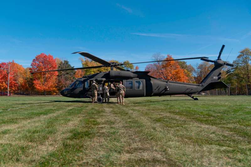 a group of people standing in front of a helicopter