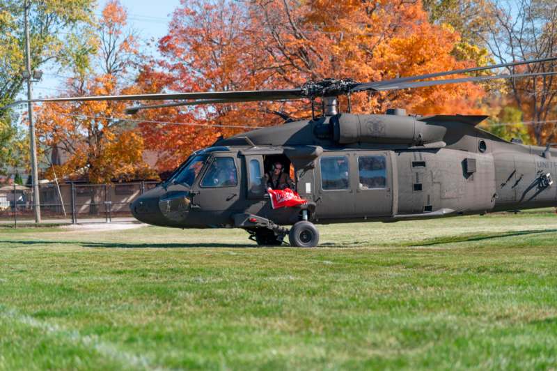 a helicopter on grass with a person in the back