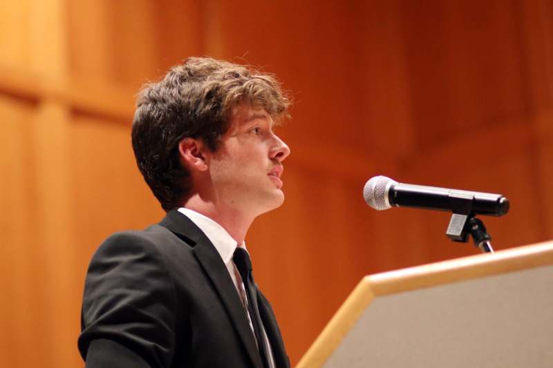 a man in a suit and tie standing at a podium with a microphone