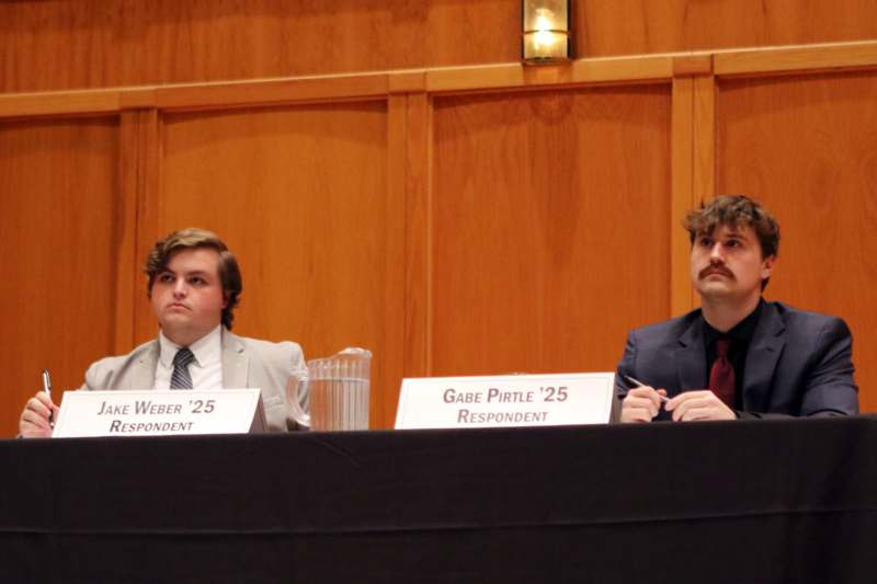 two men sitting at a table with signs