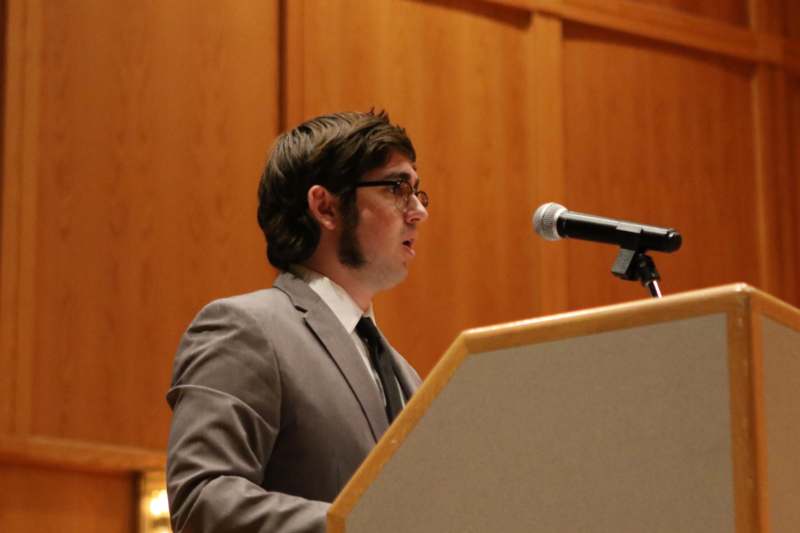 a man standing at a podium speaking into a microphone