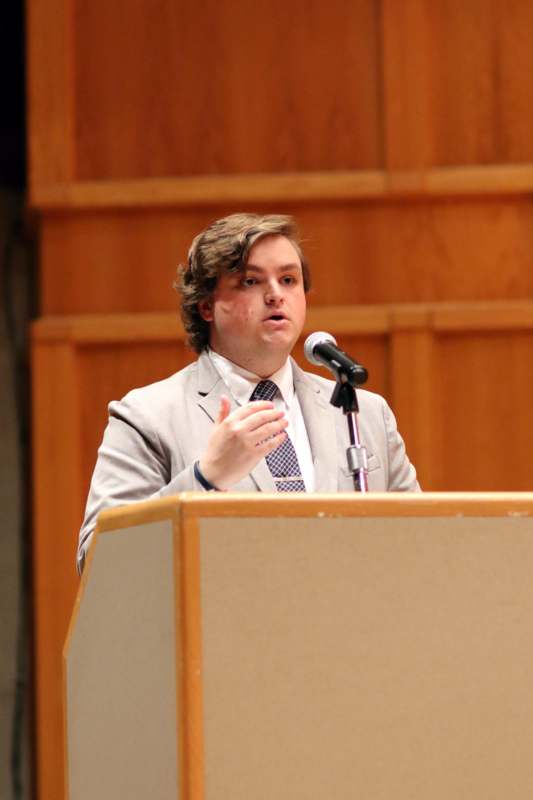 a man standing at a podium speaking into a microphone