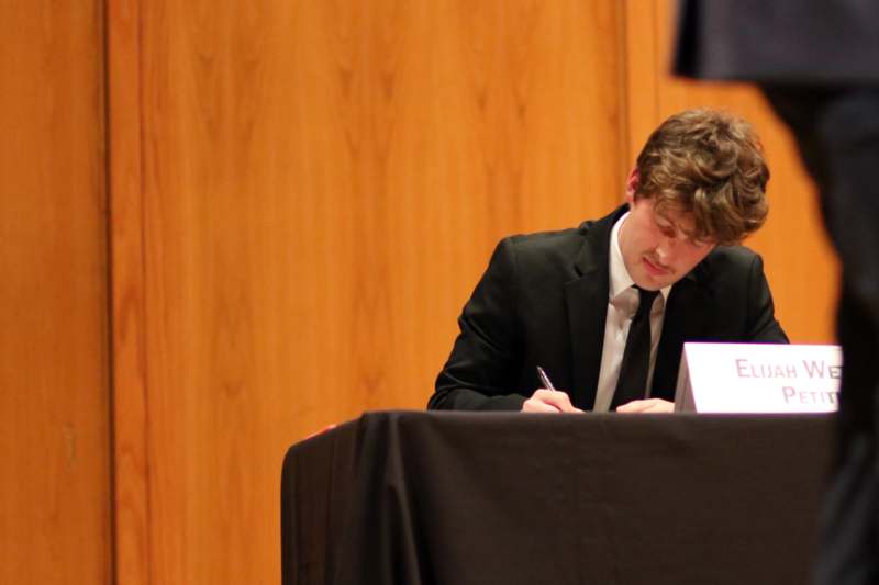 a man in a suit writing on a table