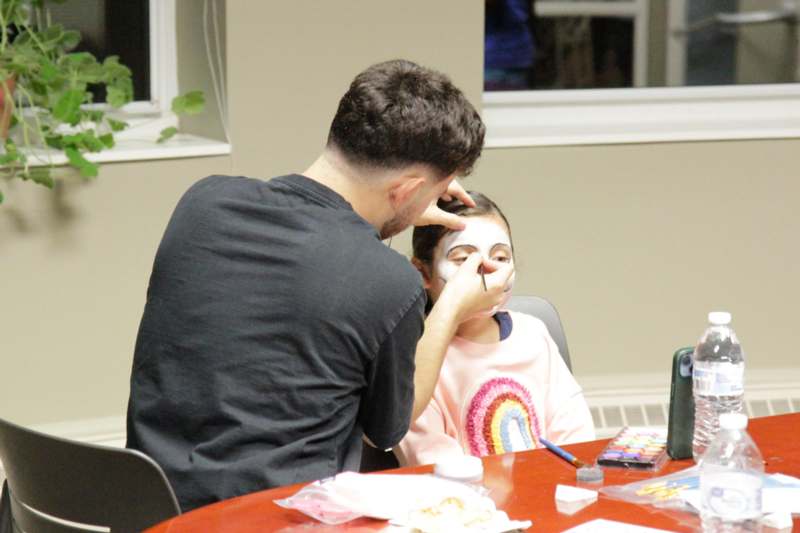 a man putting on a face paint to a girl