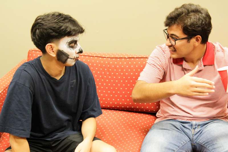 two men sitting on a couch with a face paint