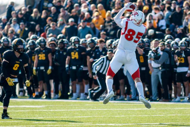 a football player jumping in the air with a crowd of people in the background