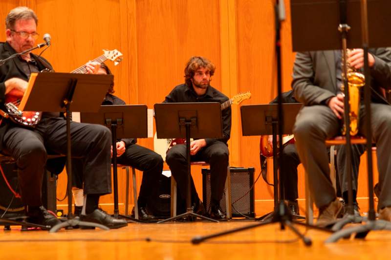 a group of people sitting on chairs playing instruments