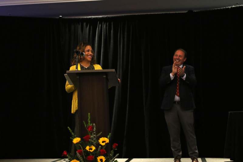 a woman standing at a podium with a man in a suit and tie