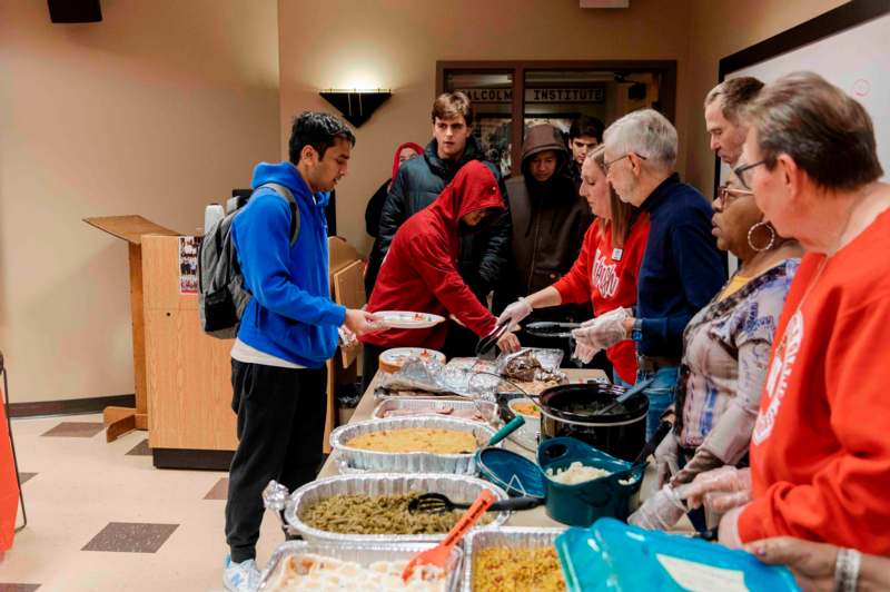 a group of people standing around a table full of food