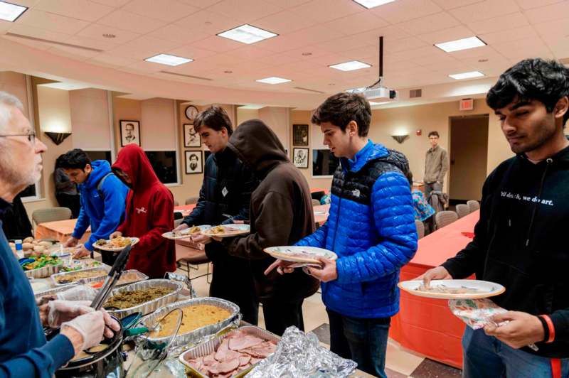 a group of people standing in a room with plates of food