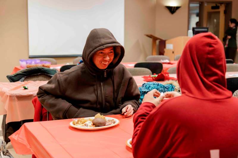 a man in a hoodie sitting at a table with food