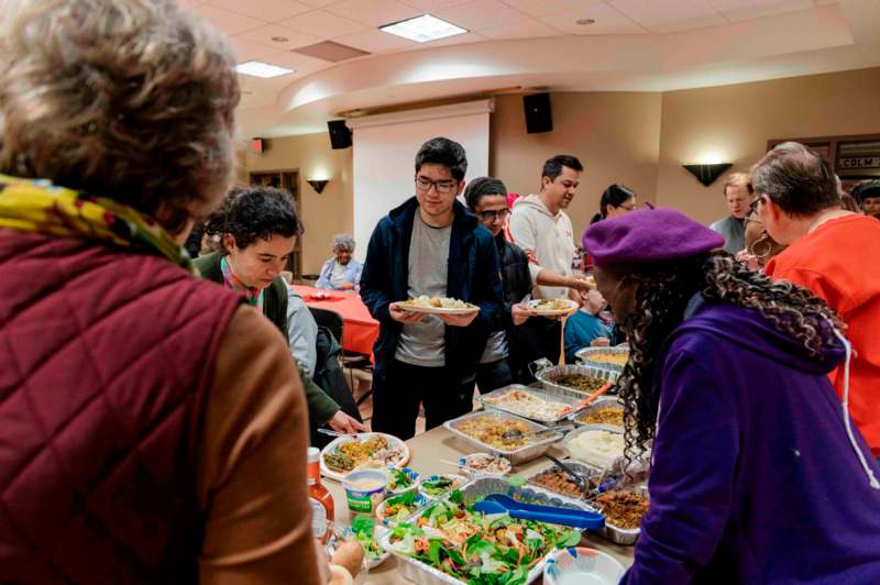 a group of people standing around a table full of food