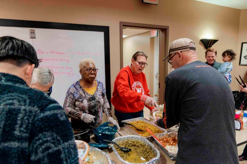 a group of people standing around a table full of food