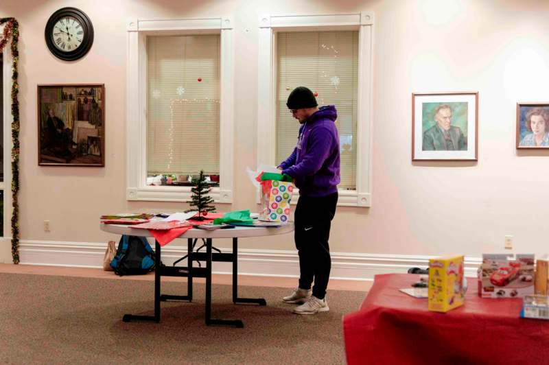 a man standing in a room with a table with presents