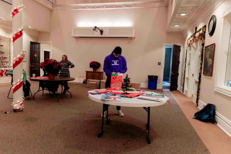 a man in a purple shirt wrapping a present on a table