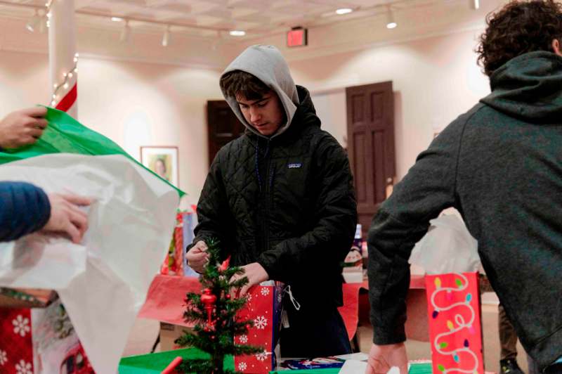 a man in a hoodie wrapping a christmas tree