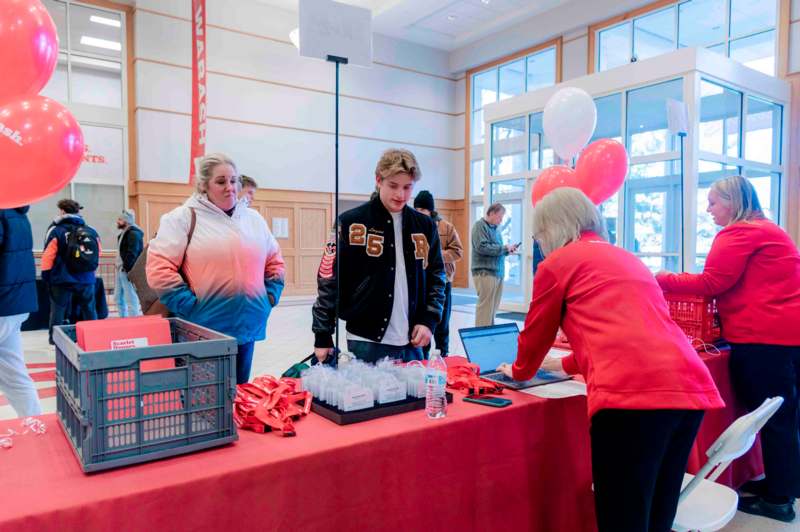 a group of people standing around a table with a red table with a red table with a red table with a red table with a red table with a red table with a red table with a red