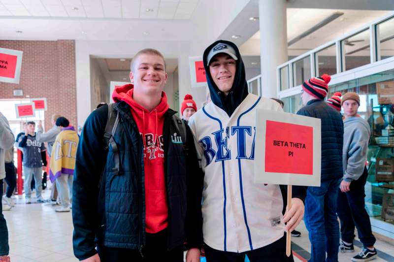 two men standing in a building holding a sign