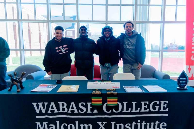 a group of men standing in front of a table with a sign