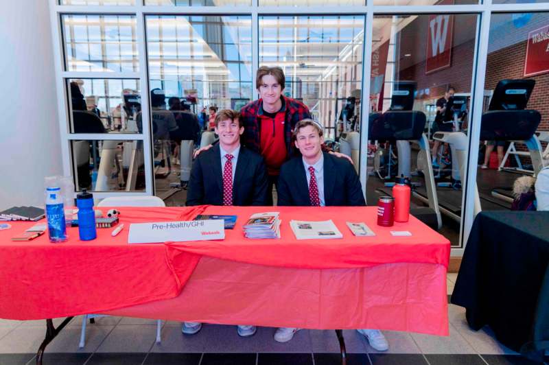 a group of men sitting at a table with a red tablecloth