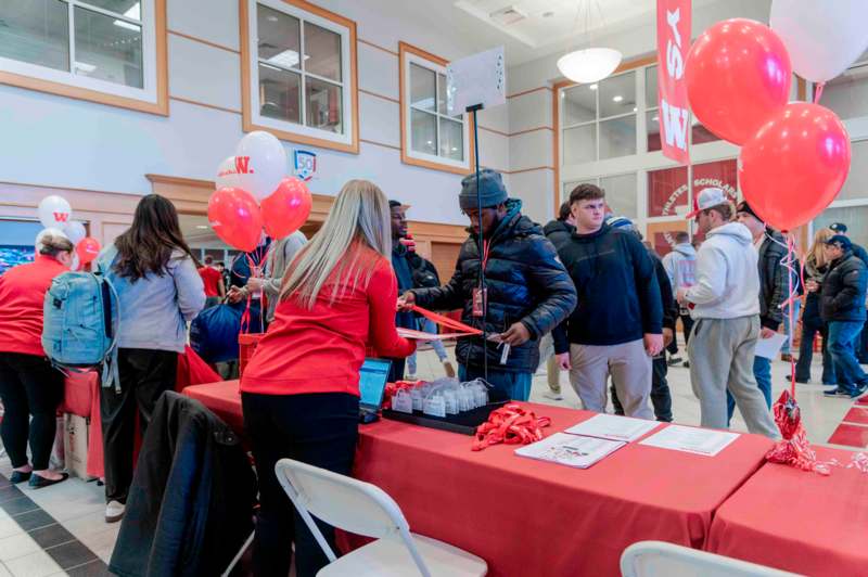 a group of people at a table with red and white balloons