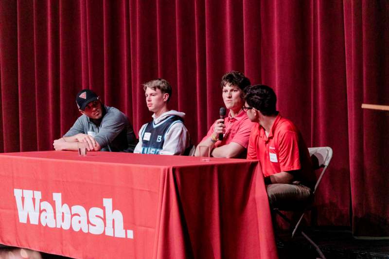 a group of men sitting at a table with a microphone