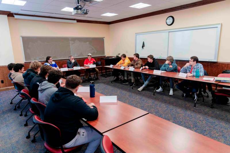 a group of people sitting at long tables in a classroom