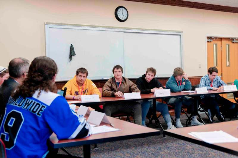 a group of people sitting at tables in a classroom