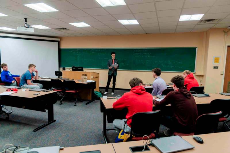 a man standing in front of a chalkboard in a classroom