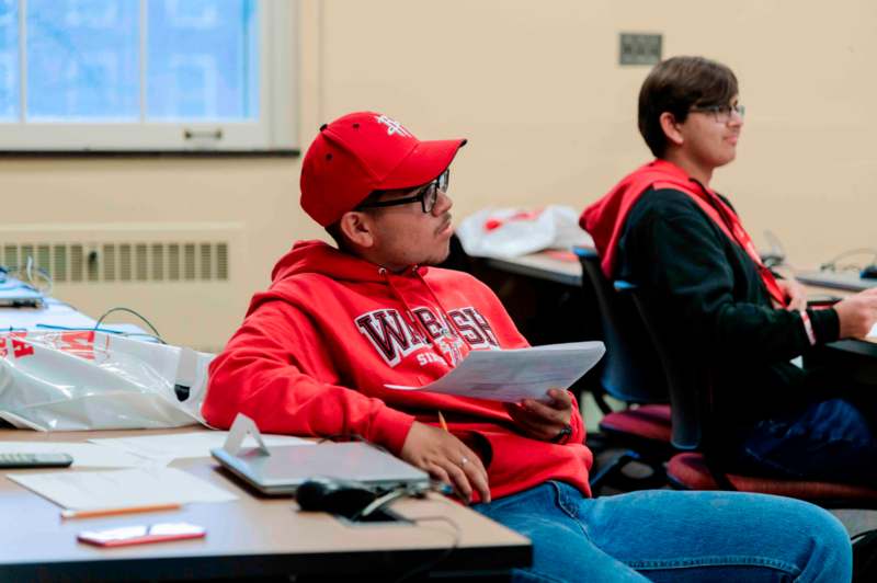 a man in a red hat and red sweatshirt sitting at a table with papers