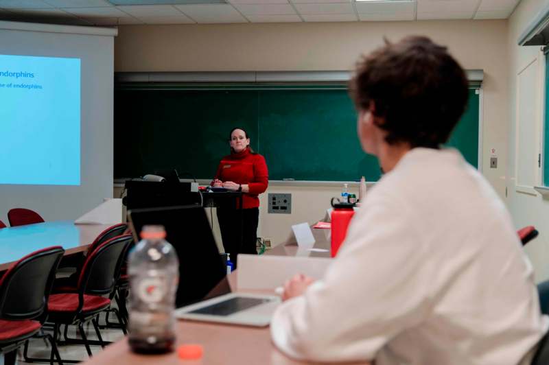 a woman standing at a podium in front of a chalkboard