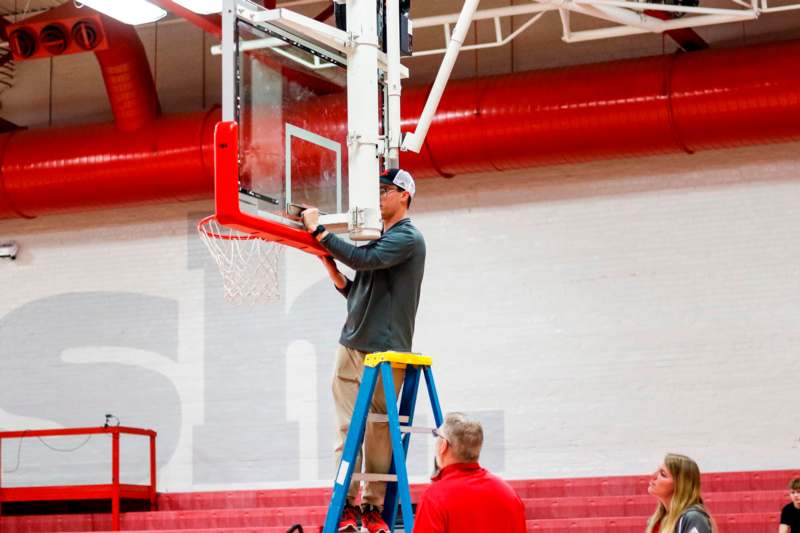 a man on a ladder holding a basketball hoop