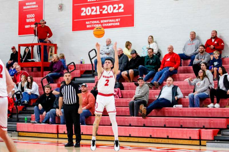 a man in a basketball uniform jumping to shoot a basketball