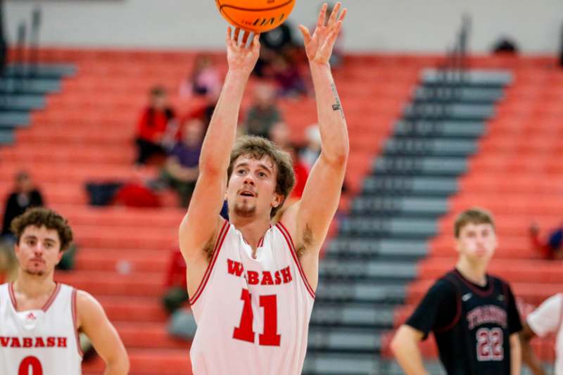 a man in a basketball uniform jumping to shoot a basketball