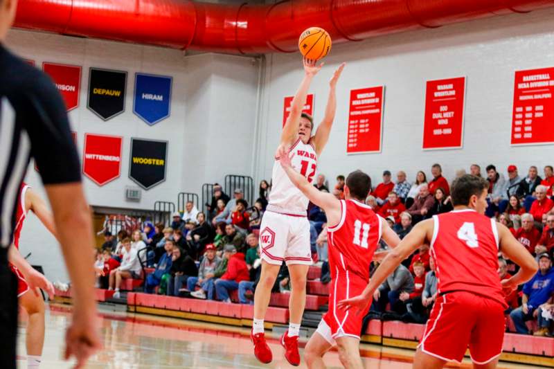 a basketball player in a red uniform jumping to shoot a basketball