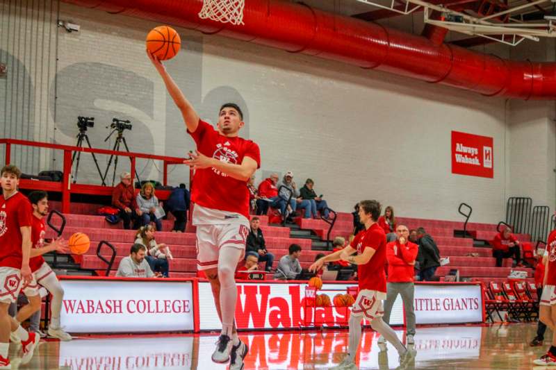 a man in a red shirt and shorts jumping to shoot a basketball