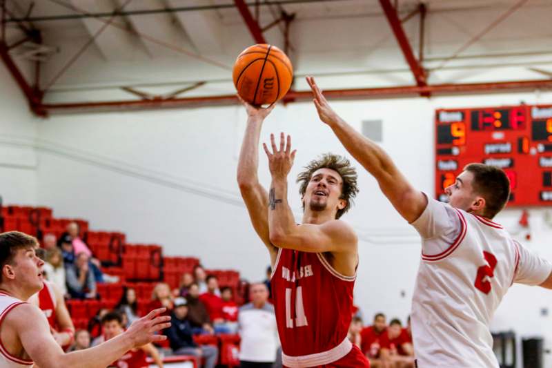 a basketball player in a red uniform jumping to shoot a basketball