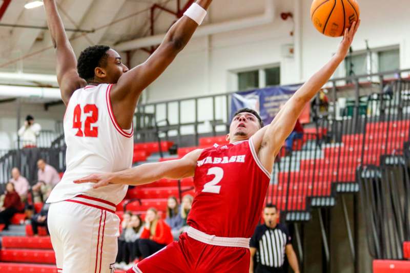 a basketball player in red uniform and white uniform in a gym