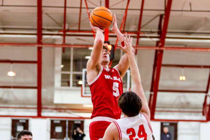 a basketball player in red uniform jumping to shoot a ball