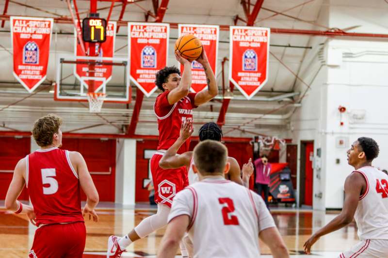 a basketball player in red uniform jumping to shoot a basketball