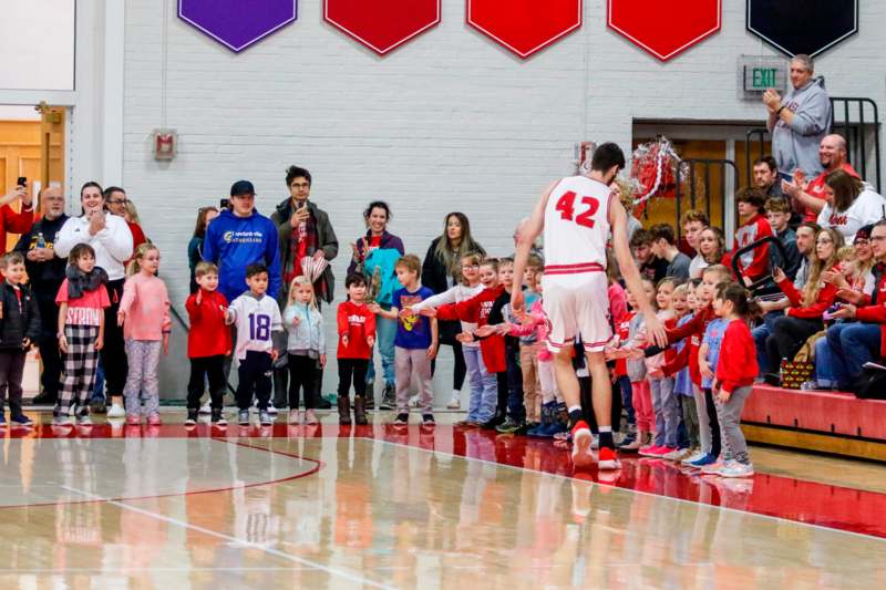 a group of kids watching a basketball player in a gym