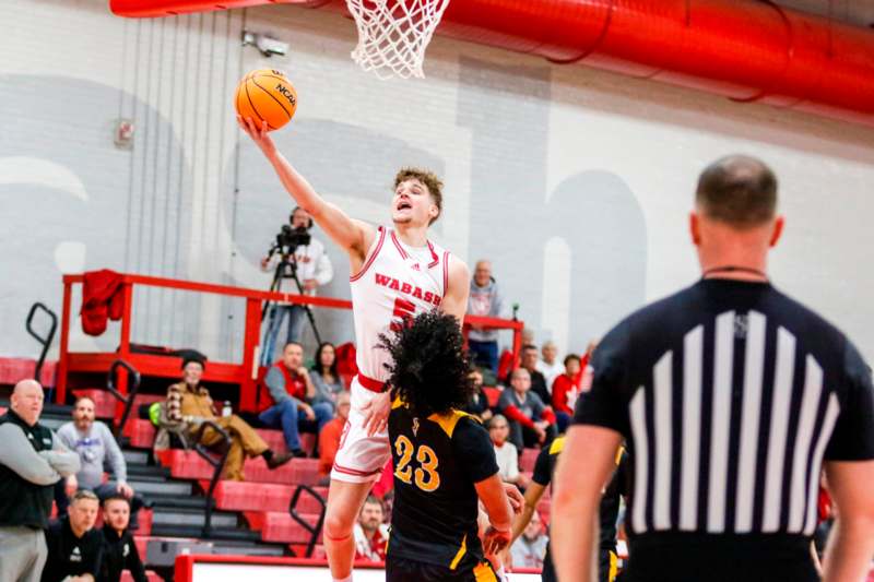 a basketball player in a red uniform jumping to shoot a basketball