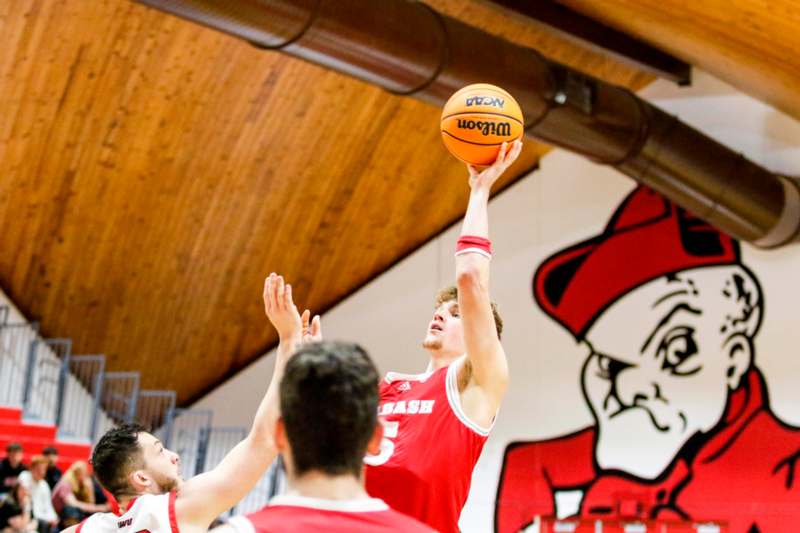 a man in a red uniform jumping to shoot a basketball