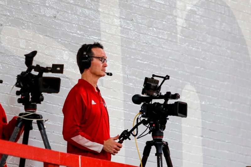 a man with headphones and microphone standing next to a camera