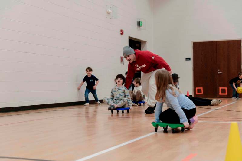 a man on skateboards with kids in a gym