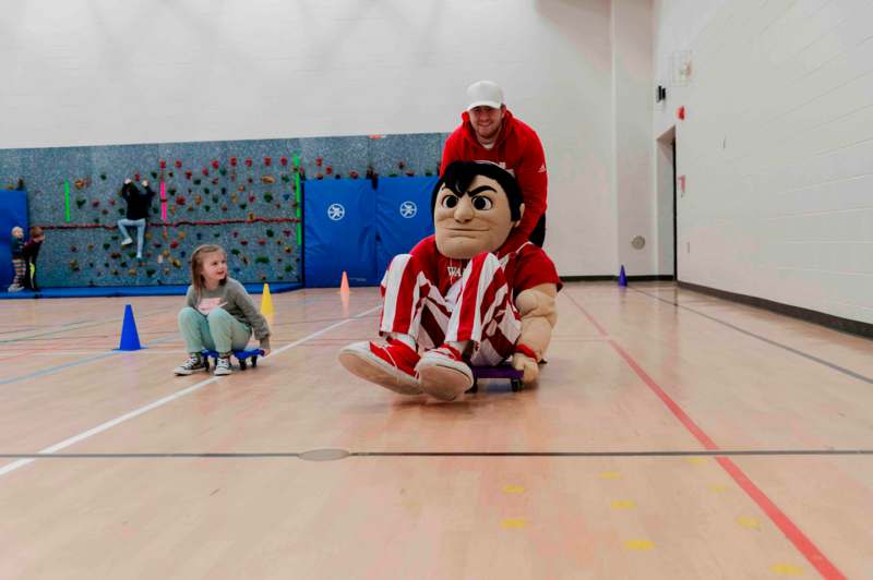 a man in a mascot garment riding a skateboard on a wooden floor