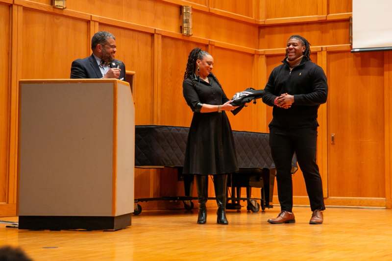 a man holding a black object with a woman standing in front of him